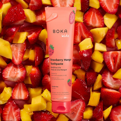 Boka Kids Strawberry Mango Toothpaste tube surrounded by sliced strawberries and mangoes.