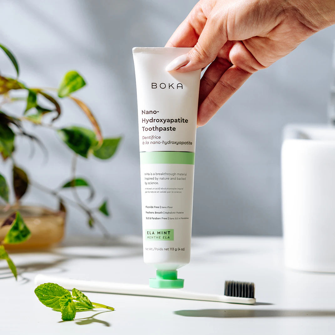 Hand holding a tube of Boka Nano Hydroxyapatite Toothpaste with a blurred background