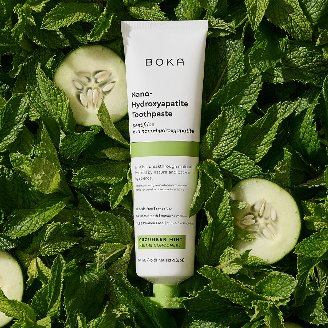 Boka Nano-Hydroxyapatite Toothpaste tube on a bed of green leaves and cucumbers