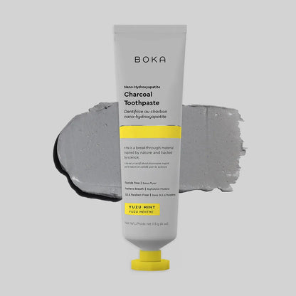 Boka charcoal toothpaste tube with gray paste smear on a light gray background