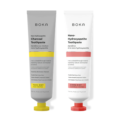 Two Boka toothpaste tubes, one with charcoal flavor and the other with cinnamon flavor, on a white background.