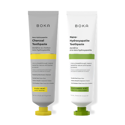 Two Boka toothpaste tubes, one with charcoal flavor and the other with cucumber mint flavor, on a white background.