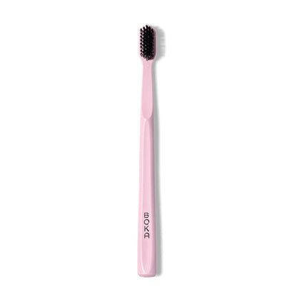 The Classic Toothbrush has pink bristles with activated charcoal and BOKA printed on the handle.