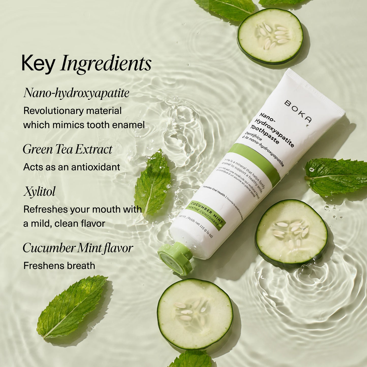 Boka Cucumber Mint toothpaste tube lying on rippling water surrounded by fresh cucumber slices and mint leaves. On the left side, text lists key ingredients: nano-hydroxyapatite, green tea extract, xylitol, and cucumber mint flavor.