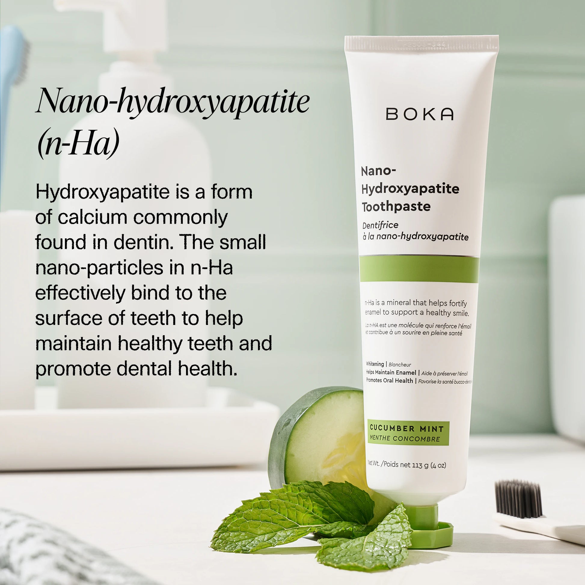A tube of Cucumber Mint n-Ha Toothpaste stands on a counter with mint leaves and a toothbrush.