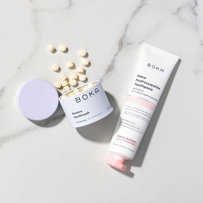 Boka products including restore mouthwash, and toothpaste on a marble surface.
