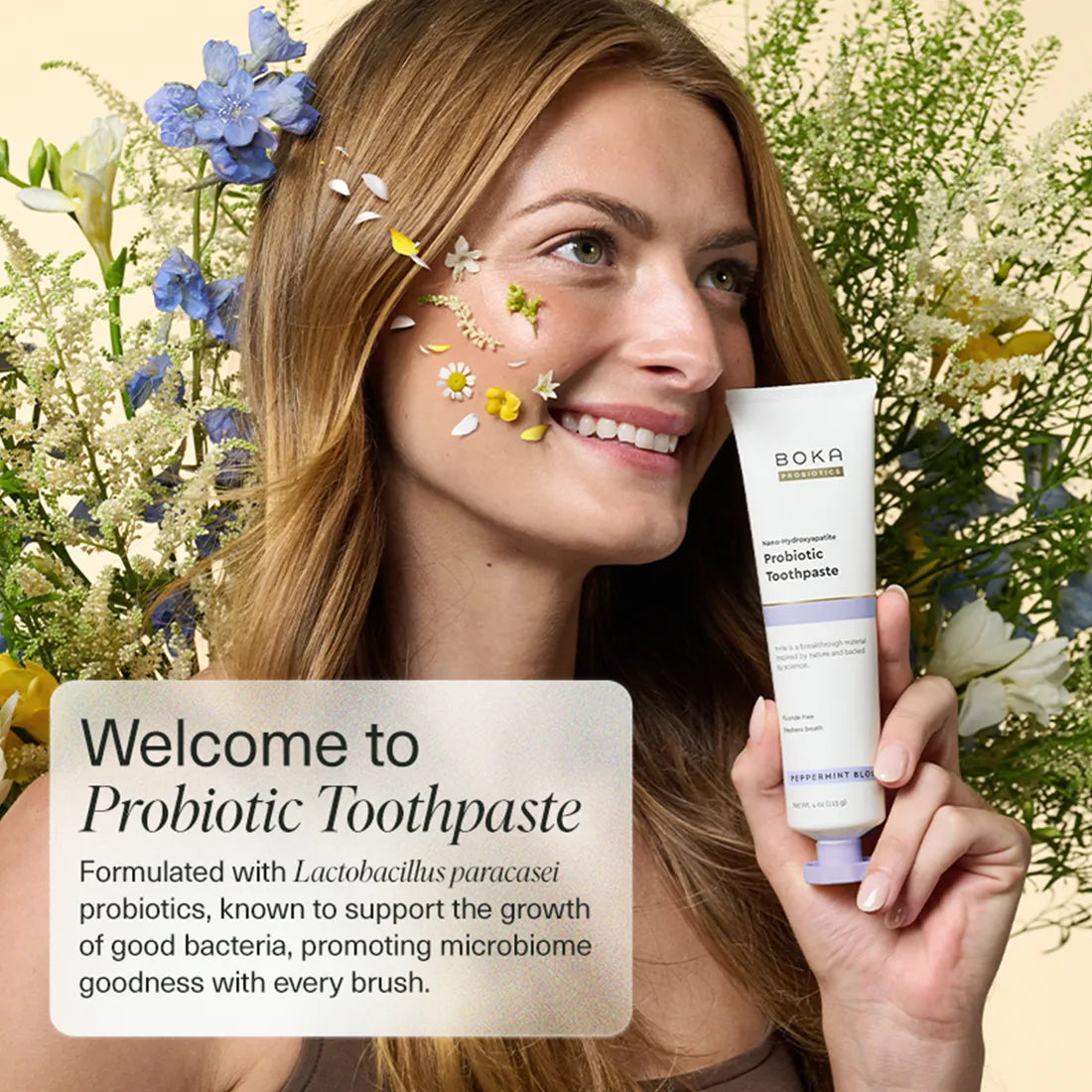 Woman holding a tube of Boka Probiotic Toothpaste with flowers in her hair and background