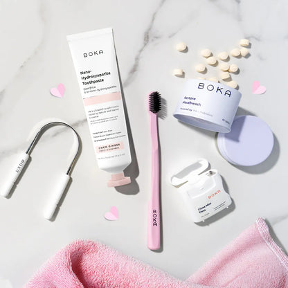 Boka dental care products including toothpaste, toothbrush, and mouthwash on a marble surface.