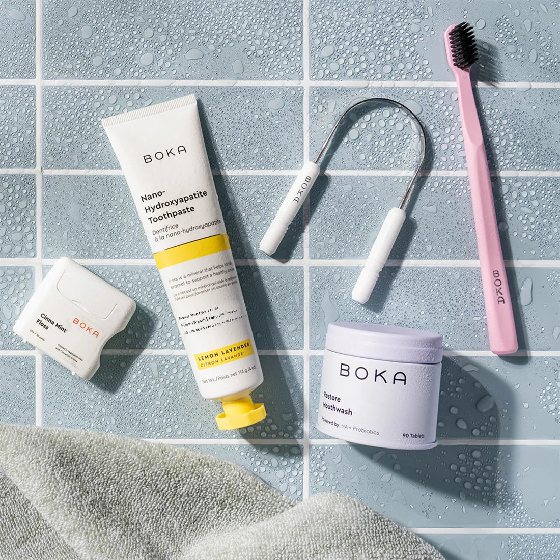 Boka dental care products including toothpaste, mouthwash, and scraper on a tiled surface.