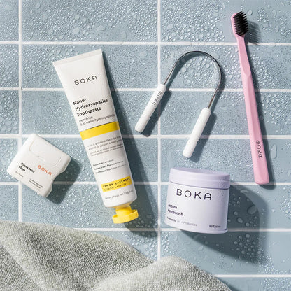 Boka dental care products including toothpaste, mouthwash, and scraper on a tiled surface.