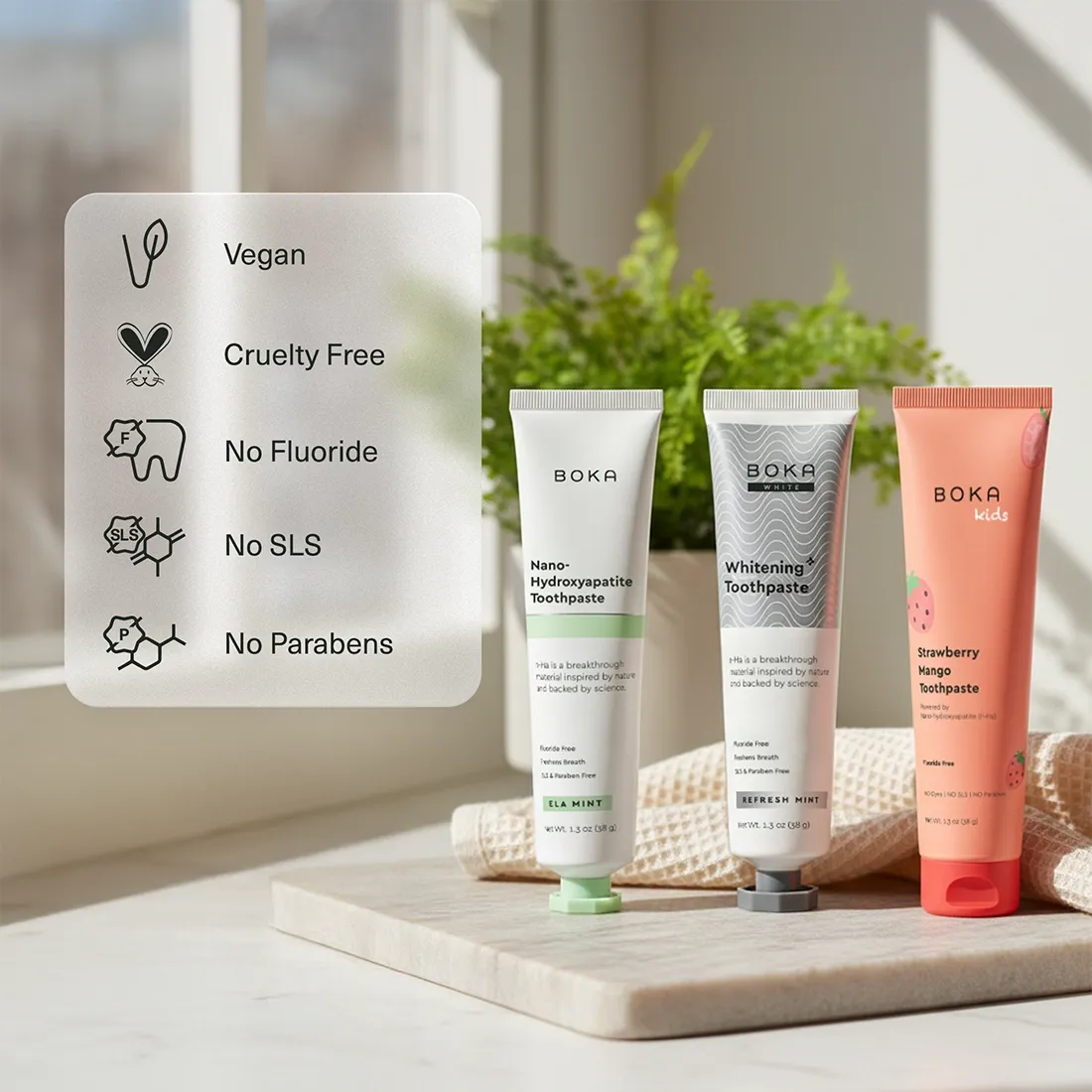 Three Boka toothpaste tubes on a wooden board with a plant in the background
