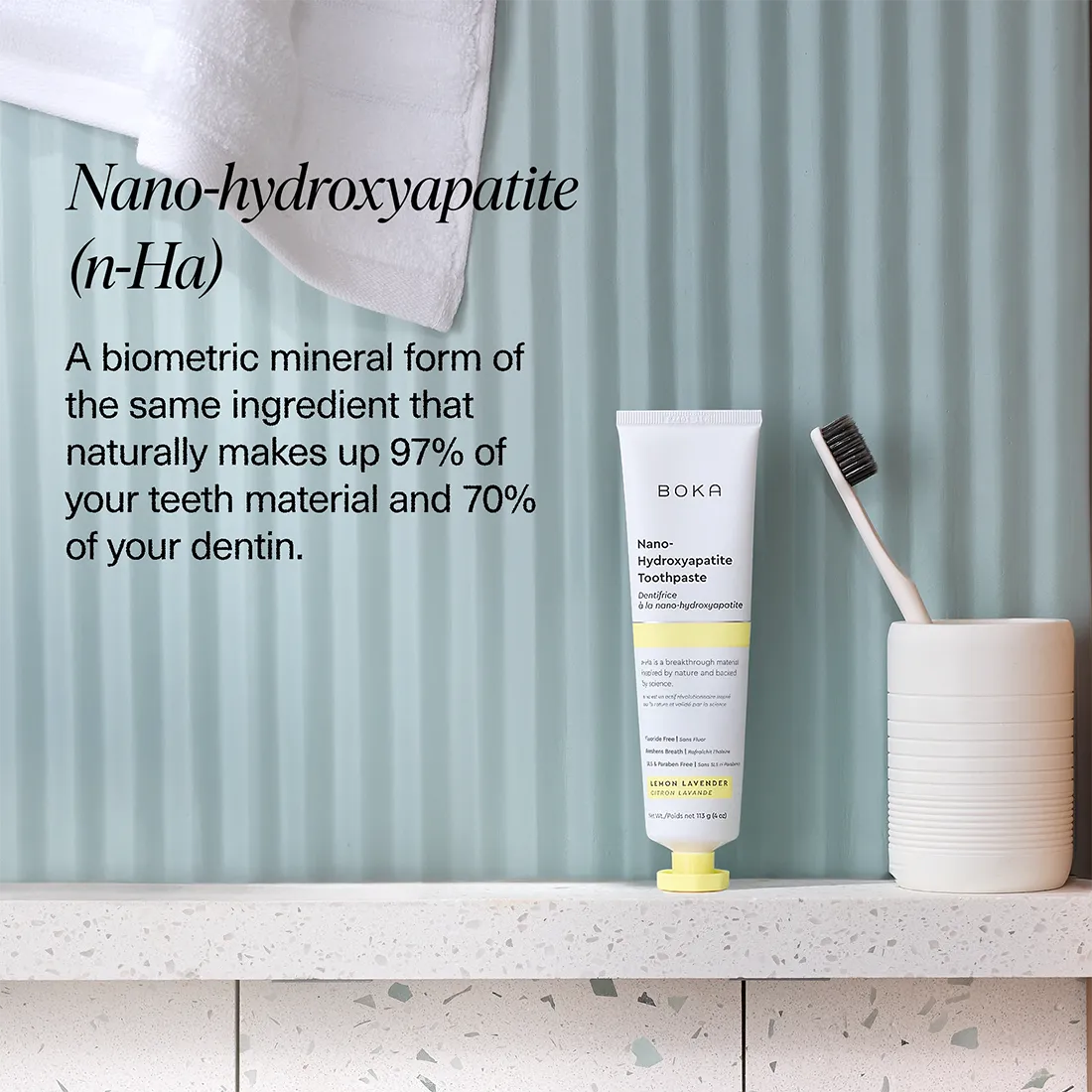 Boka Nano-hydroxyapatite toothpaste tube with a toothbrush on a light blue striped background
