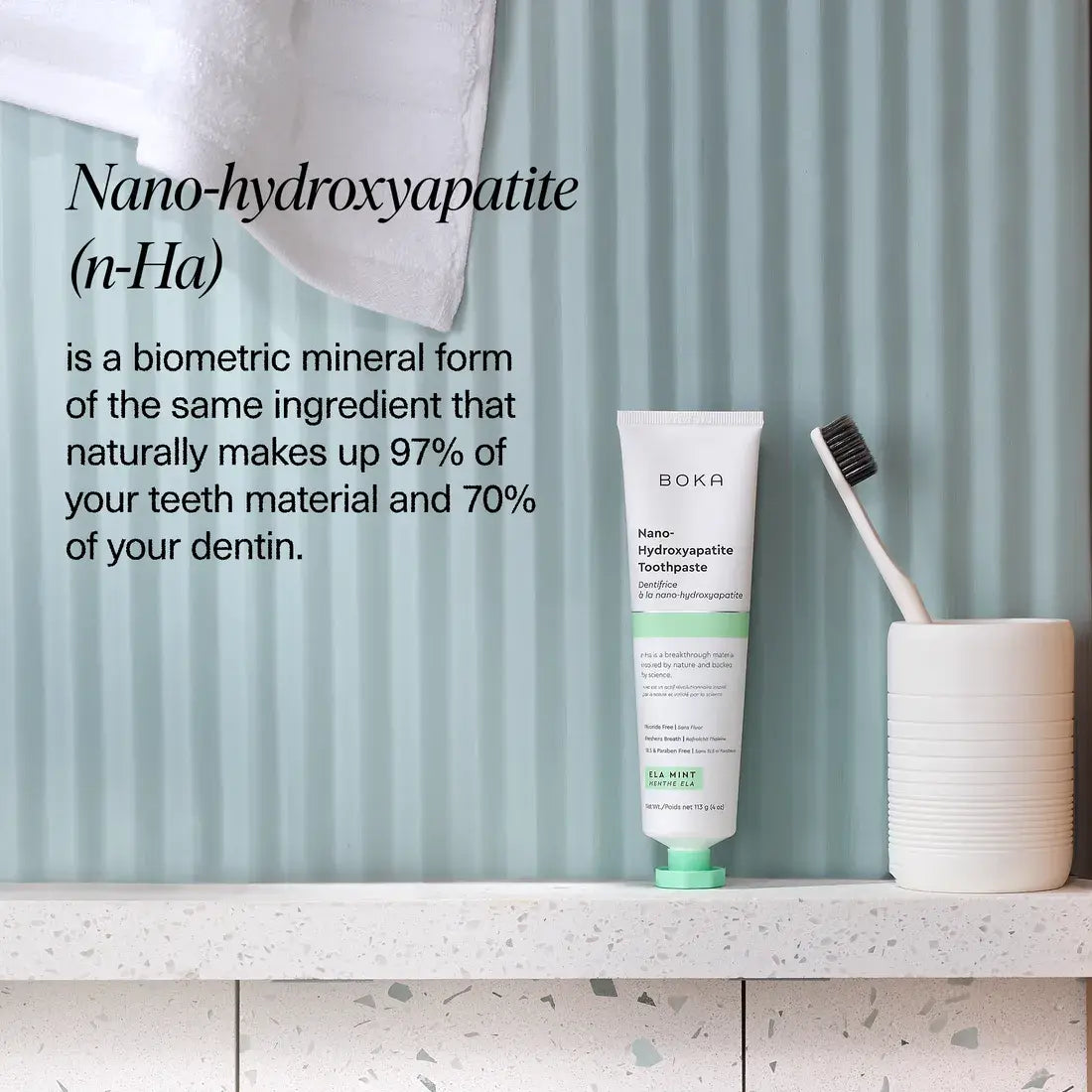 Boka Nano-hydroxyapatite toothpaste tube with a toothbrush on a shelf against a striped wall.