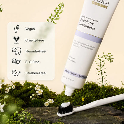 Probiotic toothpaste tube with a toothbrush and greenery on a natural background