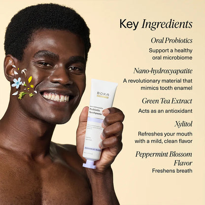 Man holding a tube of Boka Probiotic Toothpaste with key ingredients listed on a beige background