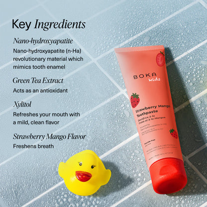 Boka Strawberry Mango toothpaste tube and toothbrush on a textured towel with mint leaves, alongside key ingredients listed