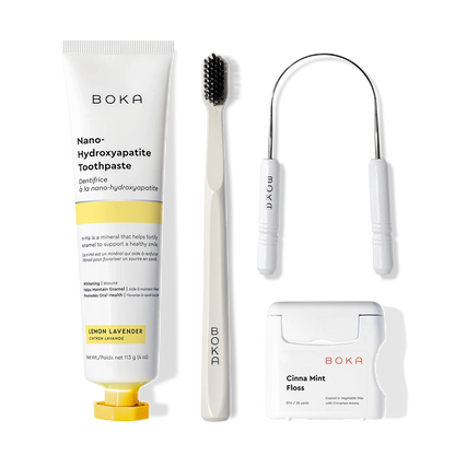 Starter Kit with toothpaste, charcoal toothbrush, tongue cleaner & floss on a plain background.