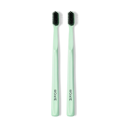 Two Classic Toothbrush 2-Packs in light green with activated charcoal bristles for gentle cleaning.
