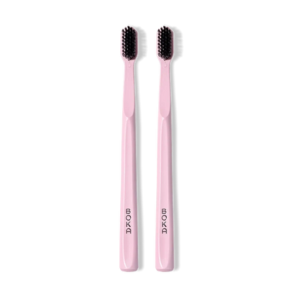 Classic Toothbrush 2-Pack: two pink brushes with black charcoal bristles, side by side.