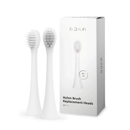 Two kids sonic toothbrush replacement heads stand beside a Boka replacement heads box.