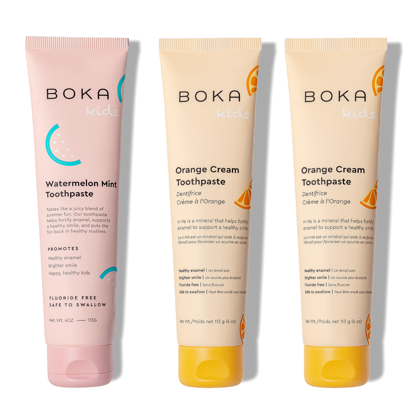 Three tubes of Boka toothpaste, two in orange cream flavor and one in watermelon mint flavor, on a white background.