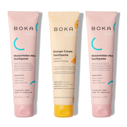 Three tubes of Boka toothpaste, two pink and one orange, on a white background.