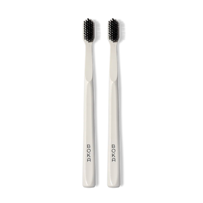 Classic Toothbrush 2-Pack: two white brushes with charcoal bristles for a gentle clean, upright.